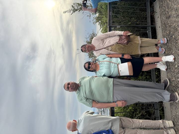 Three travellers posing at a scenic overlook under an overcast sky