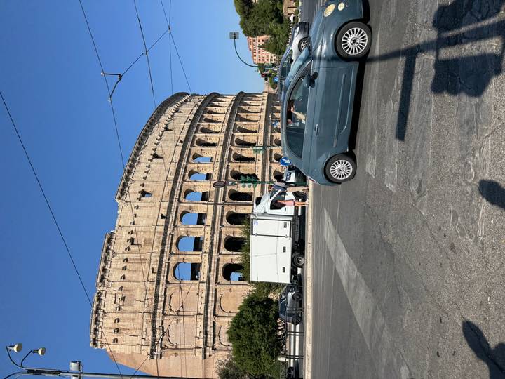 Iconic Colosseum in Rome with city traffic in the foreground