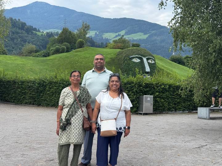 Visitors posing in front of the grass-covered giant head fountain at Swarovski Kristallwelten