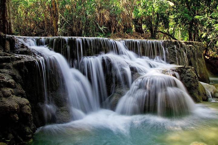 Silky turquoise cascades of Kuang Si Waterfall spilling over limestone tiers amid lush forest.