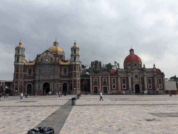 Basilica complex with yellow and red domes against a cloudy sky in Mexico City