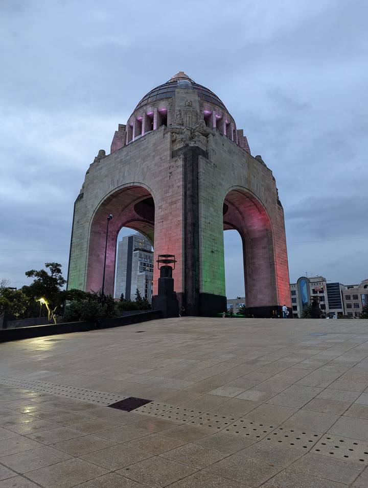 Monumento a la Revolución lit with green and red lights against an evening sky