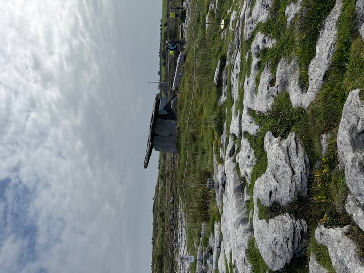Megalithic Poulnabrone dolmen standing on a limestone karst landscape under a mottled sky.