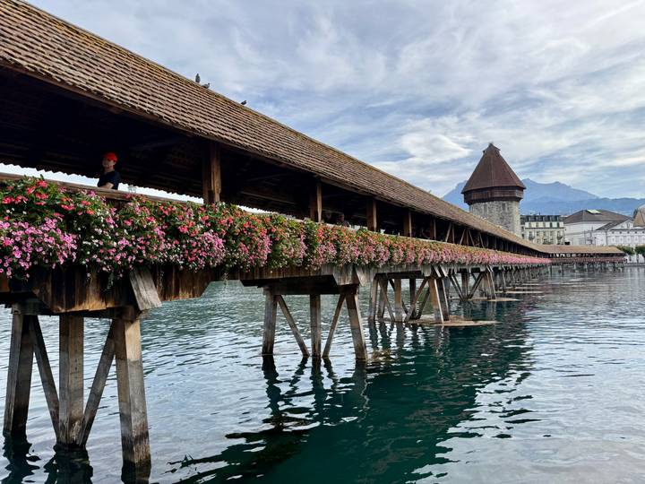 Historic wooden Chapel Bridge lined with vibrant flower boxes stretching over the calm waters of Lake Lucerne.