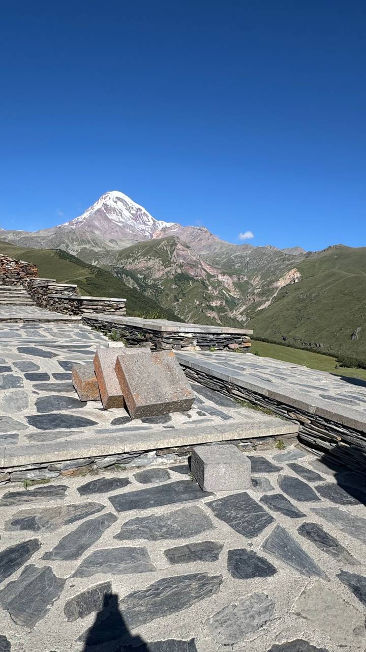 Stone terrace viewpoint overlooking dramatic green gorges and rocky peaks of the Caucasus.
