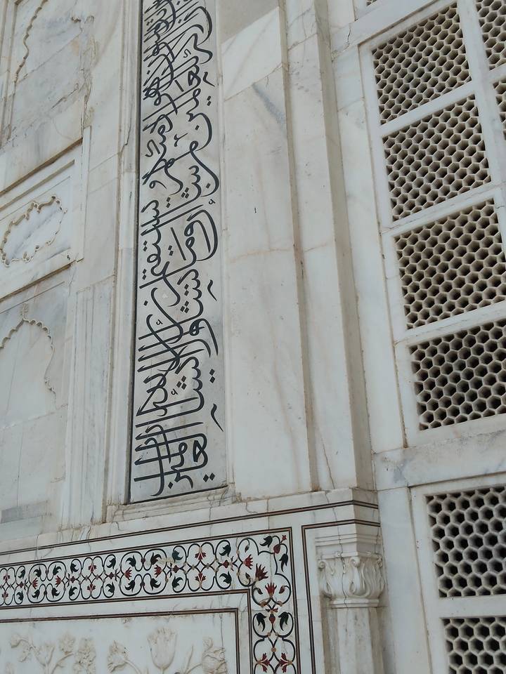 Black marble calligraphy inlaid on the pristine white marble wall of the Taj Mahal.