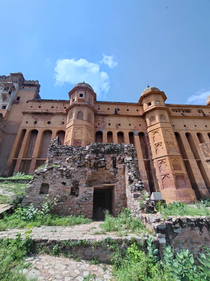 Weathered bastions and vertical windows of Amber Fort rising against a bright blue sky.