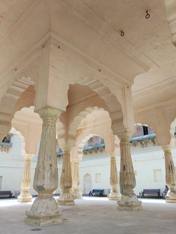 Elegant cream-colored arches and fluted pillars inside a historic palace hall.