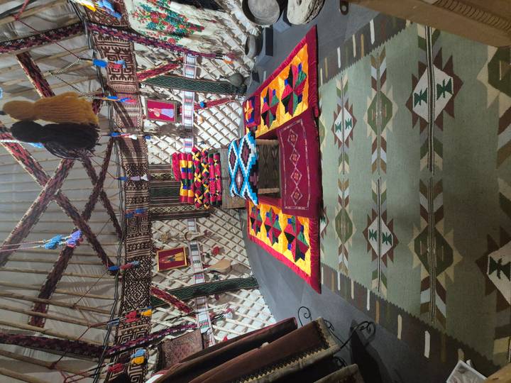 Interior of a yurt decorated with colorful patchwork textiles, rugs and traditional ornaments.