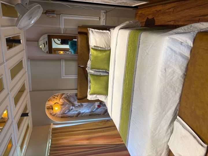 Well-made hotel room with white bedding, green accent pillows, and soft lighting.