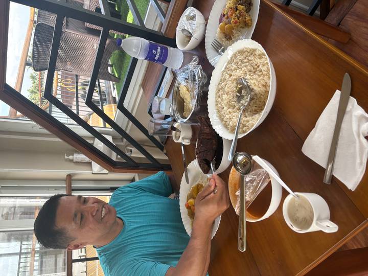 Traveler enjoying a traditional meal of rice and curries at a sunny indoor dining area.