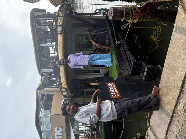 Two crew members standing on the deck of a traditional Kerala houseboat named Damodar.