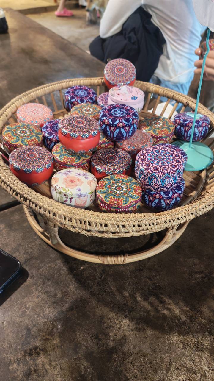 Basket filled with colourful patterned metal tins displayed at a craft market.