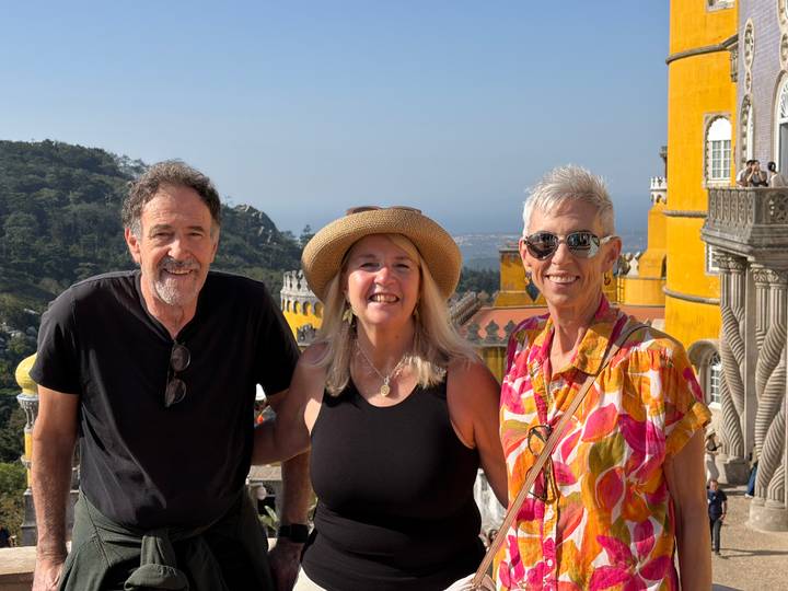 Friends smile in front of the colourful towers of Pena Palace with Sintra hills and Atlantic vista behind.