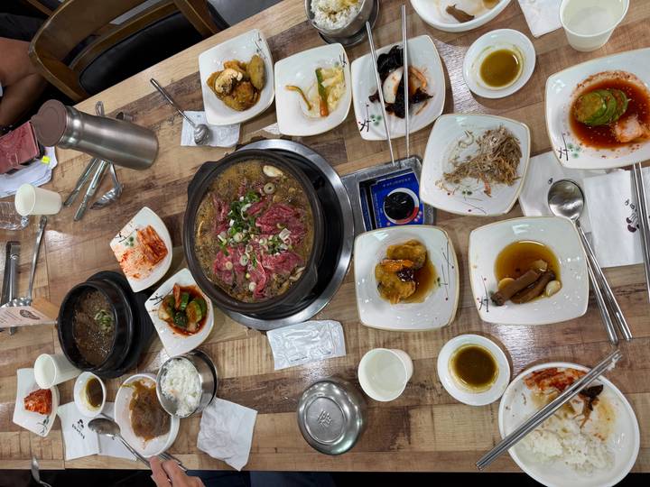 Tabletop Korean barbecue with marinated beef cooking in a hotpot surrounded by banchan dishes.