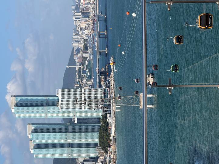 Modern Busan skyline with glass towers overlooking turquoise bay and colourful cable cars.