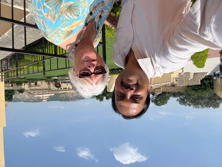 Selfie of two people at Amber Fort gardens with green hills and blue sky behind.