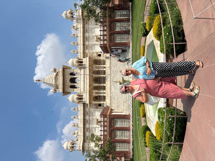 Two women pose in front of the white marble Jaswant Thada monument on a sunny day.