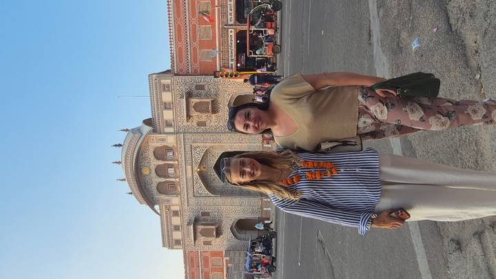 Two travellers in front of the ornately painted entrance gate of Jaipur’s City Palace complex.