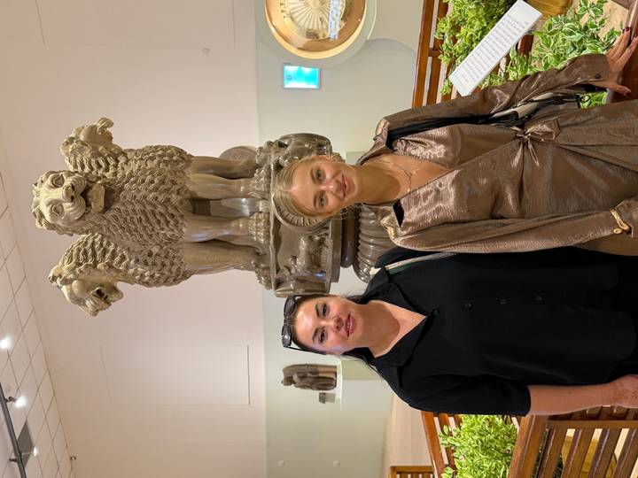 Two women inside a museum standing before the famous Ashoka lion capital sculpture.