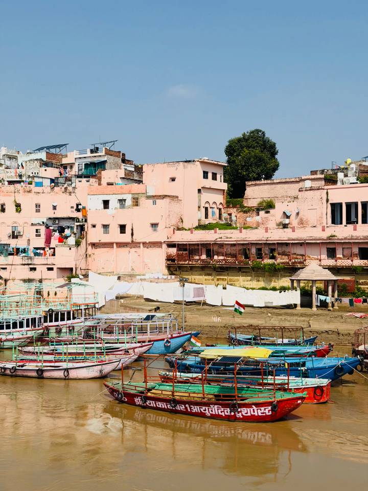 Colourful riverside buildings and moored boats along the ghats with the Indian flag fluttering.