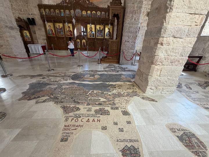 Ancient mosaic map of the Holy Land covers the church floor in Madaba behind rope barriers.