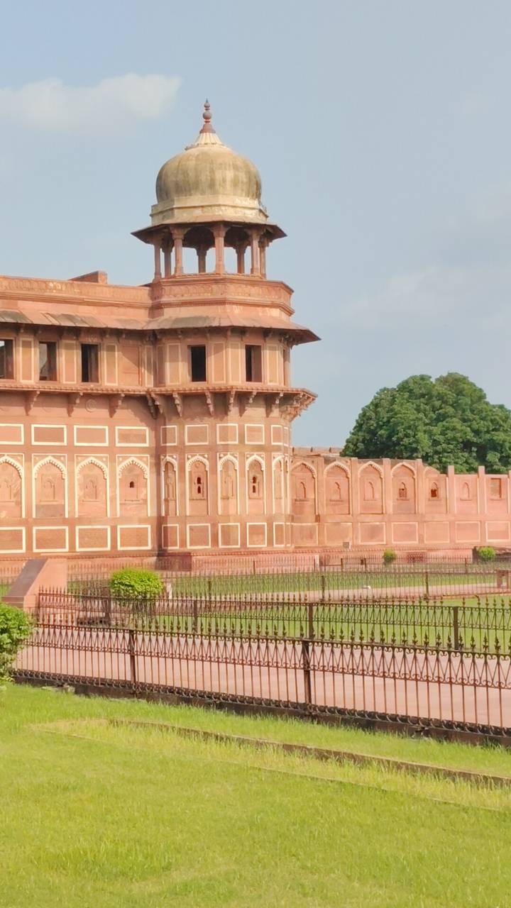 Close-up of ornate red sandstone walls and domed bastion of a Mughal fort.