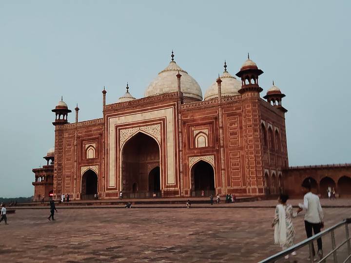 Side mosque within the Taj Mahal complex set in an open courtyard with scattered visitors.