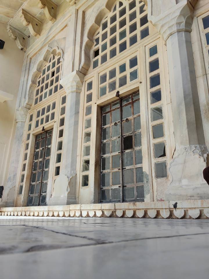 Weathered palace façade featuring tall grid windows with missing panes.