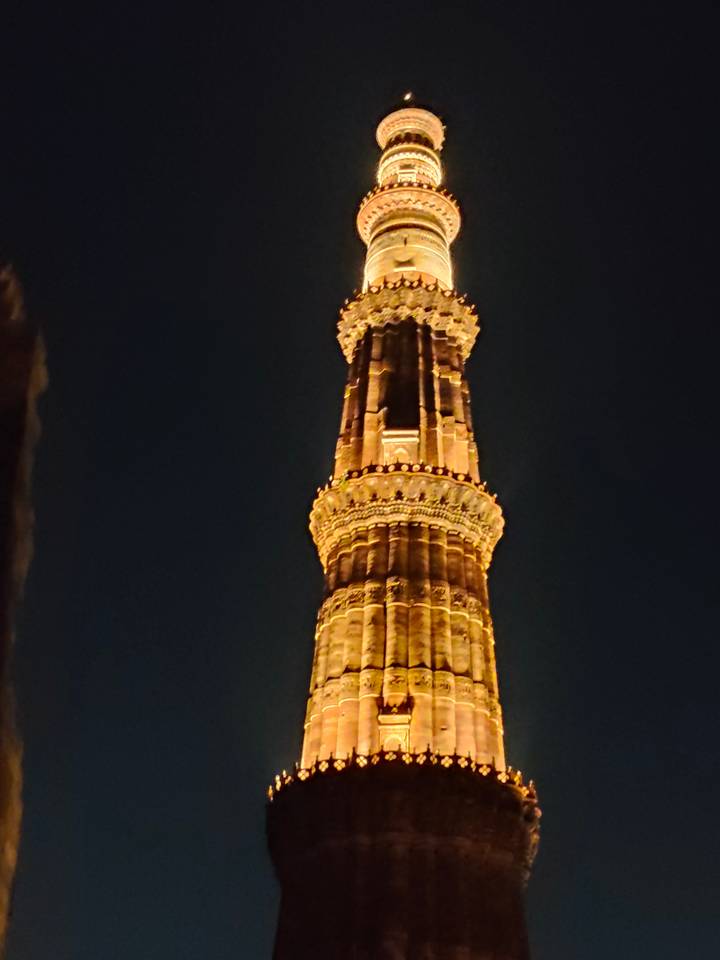 Close view of an illuminated stone tower against a dark night sky.