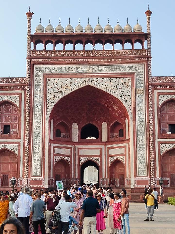 Detailed façade of the Taj Mahal gateway showcasing red sandstone and white floral inlay.