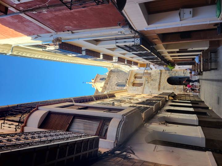 Narrow alleyway lined with tall traditional buildings leading to an ornate stone church façade in Caravaca de la Cruz.