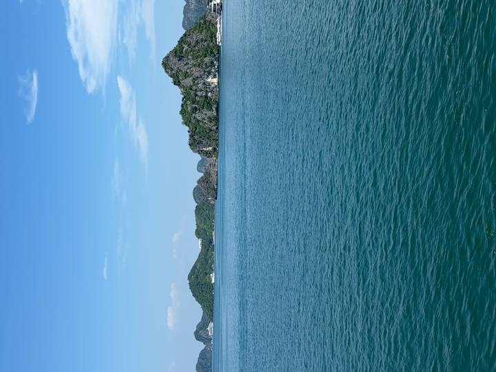 Expansive turquoise bay with calm water and forest-covered limestone islands under a clear blue sky.