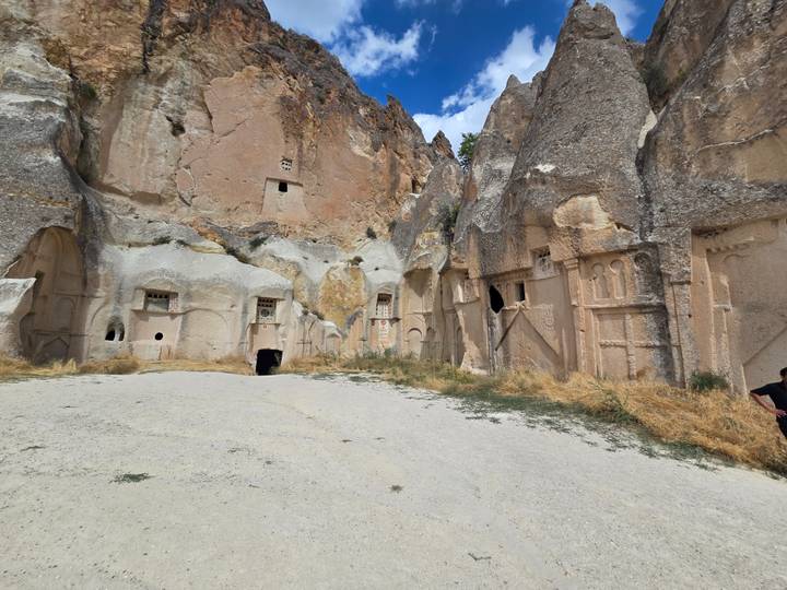 Open courtyard surrounded by tall rock-cut church facades carved into rose-colored cliffs.