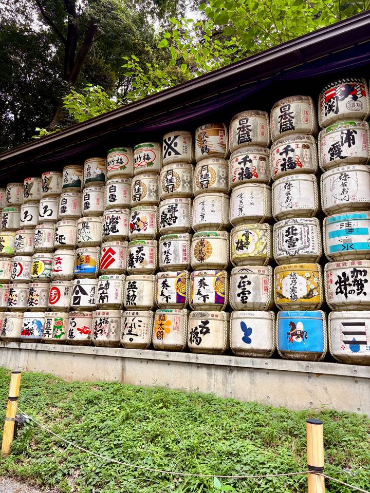 Stacks of decorative sake barrels with Japanese calligraphy at a shrine entrance.