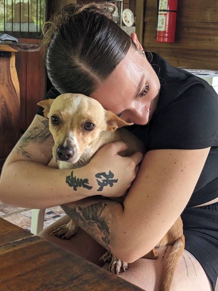 Traveler lovingly hugs a small rescue dog indoors.