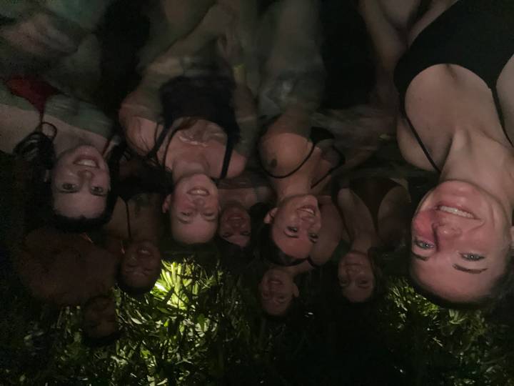 Nighttime selfie of friends relaxing in a steamy jungle hot spring pool.