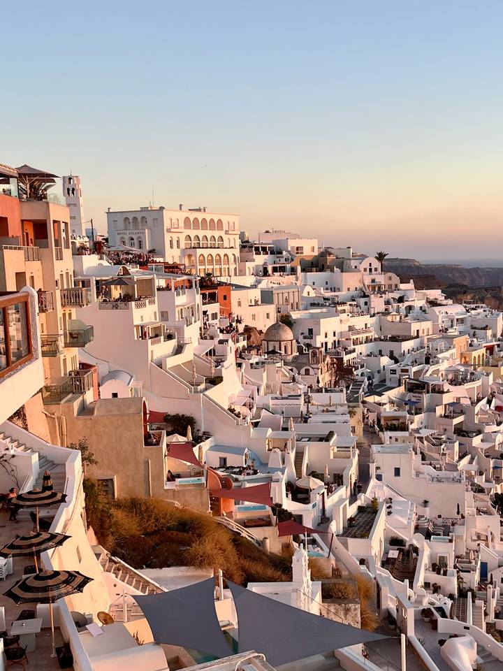 Sweeping sunset view of whitewashed cliff-side houses cascading down the caldera in Santorini