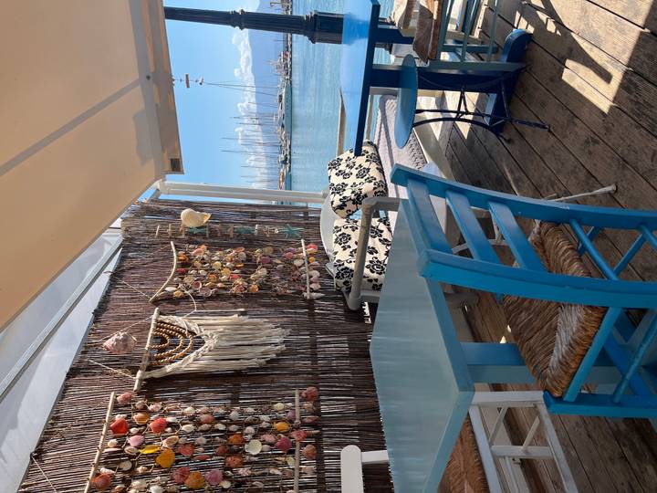 Cozy seaside café with blue furniture and nautical décor overlooking a marina of sailboats