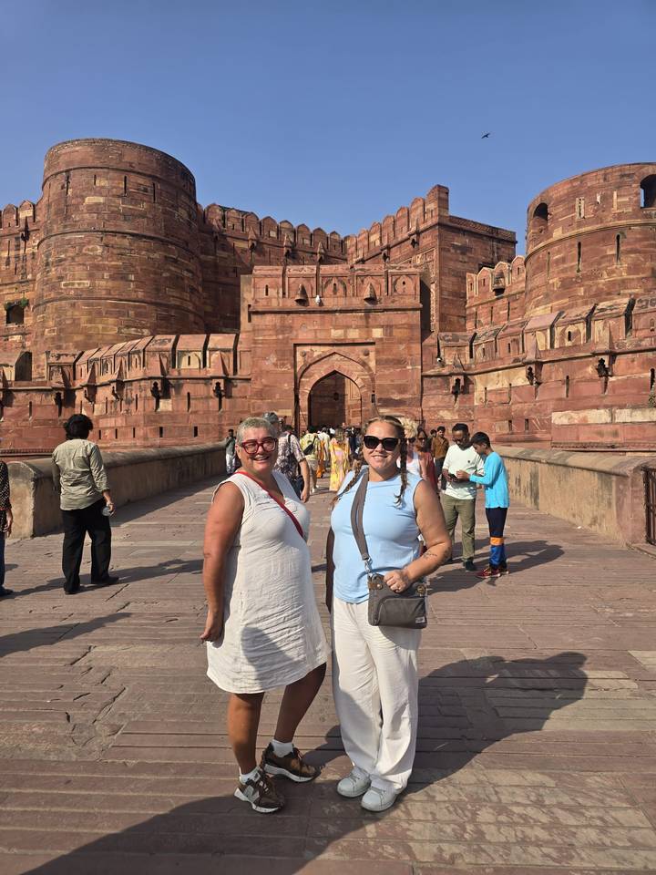 Two travellers pose on the causeway leading to the imposing red-sandstone gateway of Agra Fort.
