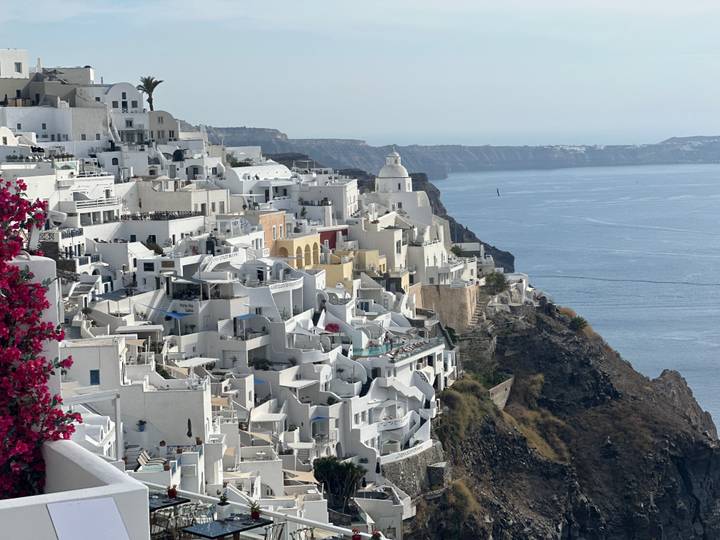 Spectacular cliff-side panorama of white Cycladic houses cascading toward the blue Aegean Sea.