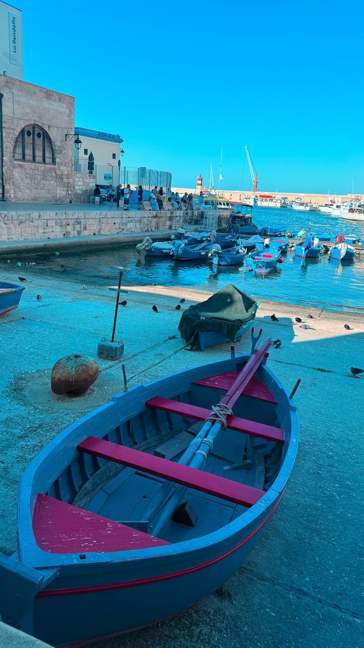 Close-up of colorful small boats and fishing gear along a concrete harbor ramp.