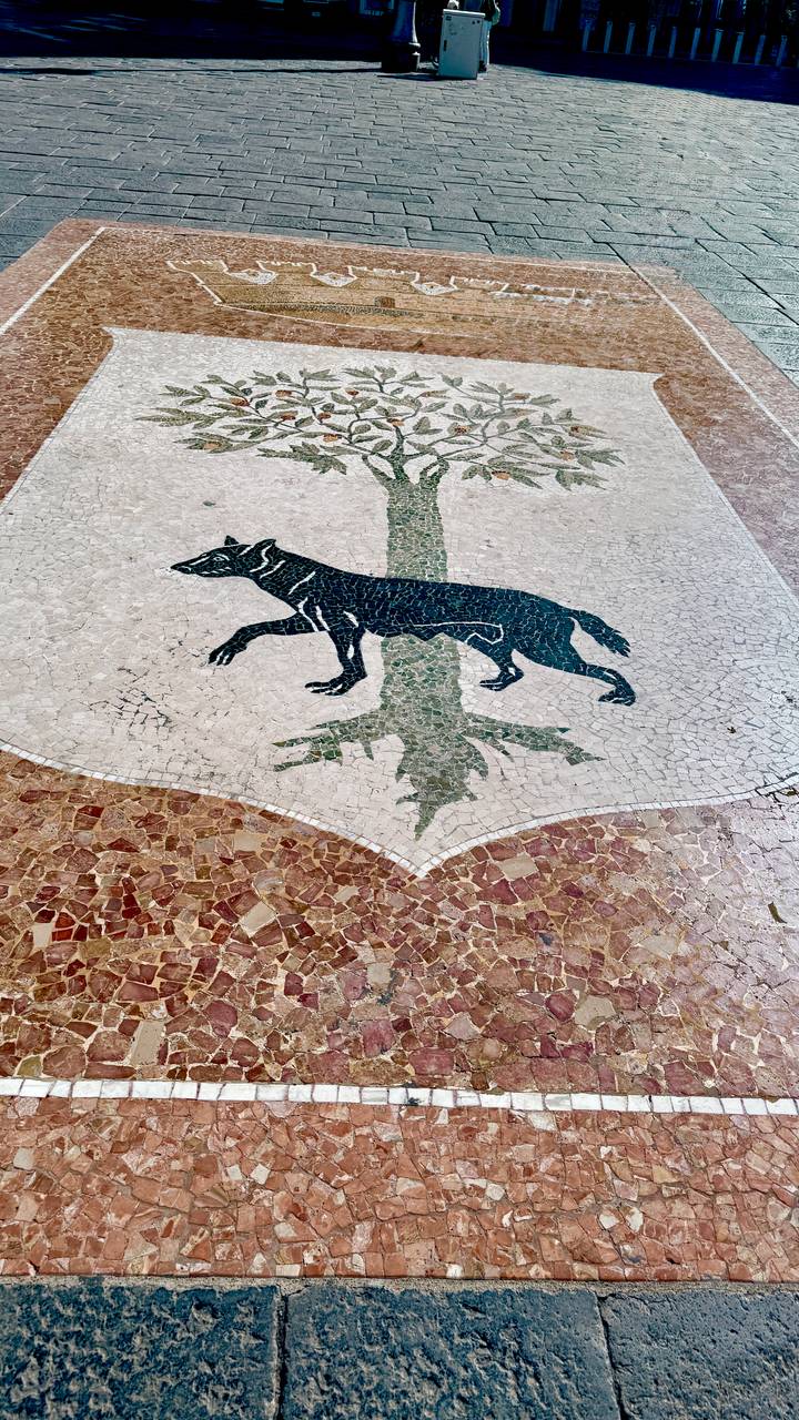 Mosaic floor depicting a black wolf standing beside a stylized green tree trunk.