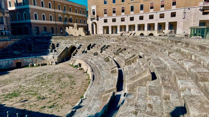 Stone seating tiers of an ancient Roman amphitheater in bright sunlight.