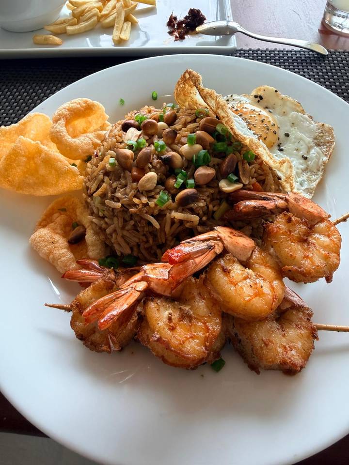 Plate of Sri Lankan fried rice topped with prawns, peanuts, egg and crisp accompaniments.