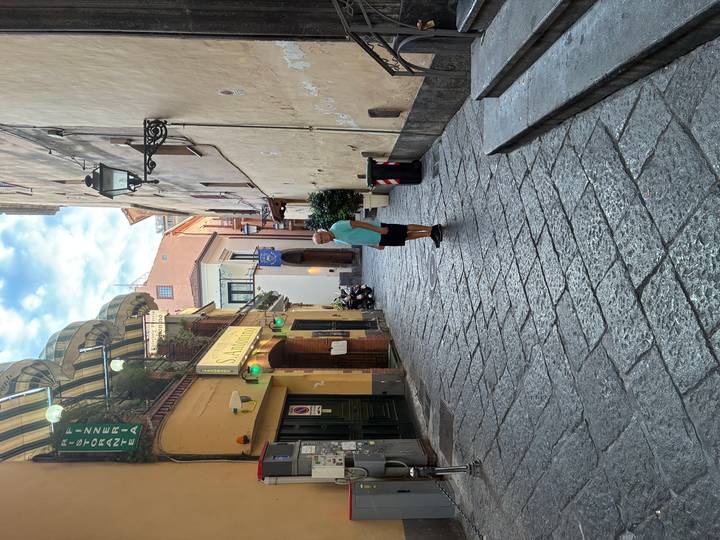 Quiet narrow alleyway with stone pavement and a lone traveller standing under awnings.