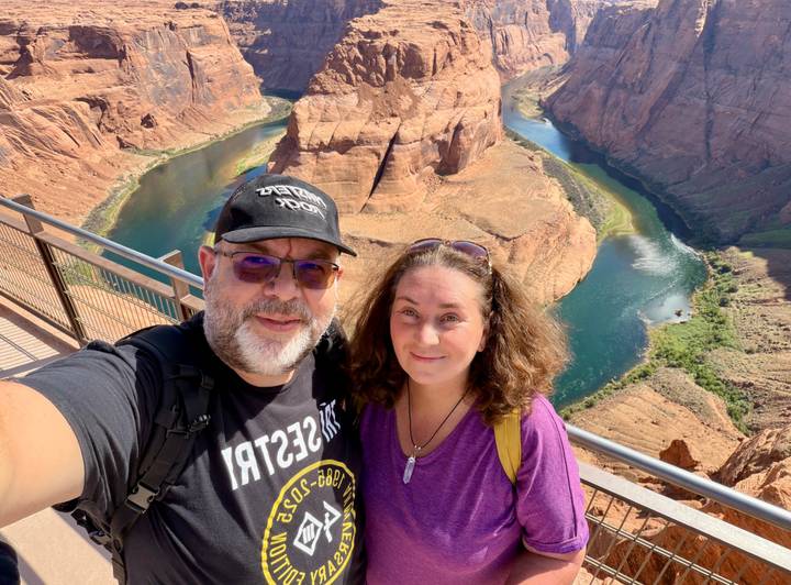 Selfie of smiling couple on viewpoint above iconic Horseshoe Bend meander of the Colorado River.