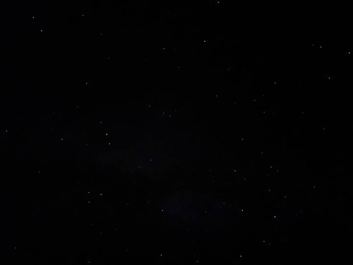 Night sky filled with scattered stars over a pitch-black desert scene.