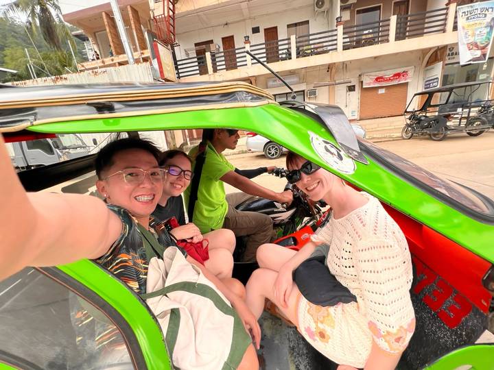 Travellers smile from inside a brightly painted tricycle as the driver readies to depart a Philippine town street.
