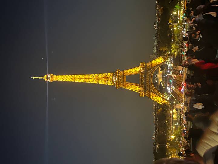 Nighttime Eiffel Tower illuminated in gold above a bustling plaza